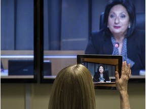 Journalists take photos of a TV screen showing Charbonneau Commission Justice France Charbonneau Jan. 13, 2014.