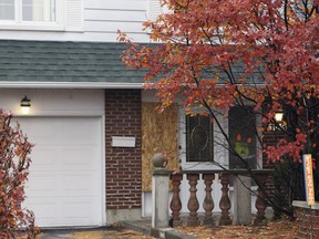 A board covers a window on the front of a home on Roger-Pilon St. in Dollard des Ormeaux, west of Montreal on Sunday Nov. 1, 2015.