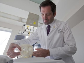 Plastic and reconstructive surgeon Dr. Daniel Borsuk with a 3D model of a patient's skull at his clinic, in Montreal, Tuesday Nov. 10, 2015.  He helped rebuild the patient's mouth and cheekbone after he suffered a trauma to the face.