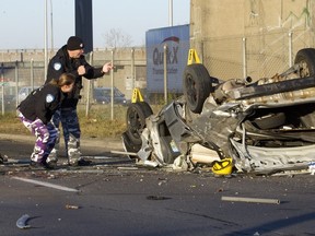 Police investigate a crash scene after a driver lost control of a car and crashed through the railings from the Hymus overpass unto the highway 40 east service road, in Montreal, Monday November 10, 2015 at 12:20 PM. The driver is in critical condition in hospital.