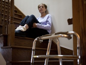 Anna Biason sits on the stairs at her home in Montreal on Wednesday, Nov. 11, 2015. When doctors refused to operate on her shoulder, Biason paid to have the surgery done privately, charging it to her credit card --something she did again a year later for toe surgery.