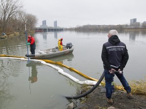 A crew cleans debris from water at the exit to a channel leading from the St-Pierre sewage discharge point in Verdun, Montreal, Thursday November 12, 2015.