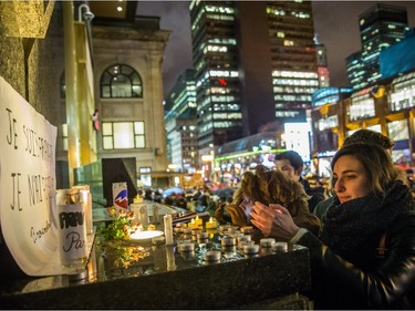 A woman lights a candle as people gather in front of the French consulate in Montreal for a night-time vigil for the victims of the terrorist attack in France on Friday, Nov. 13, 2015.