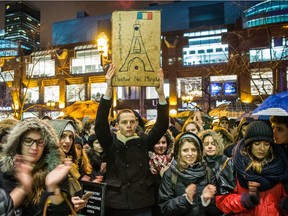 People gather in front of the French consulate in Montreal for a night-time vigil for the victims of the terrorist attack in France on Friday, Nov.  13, 2015.