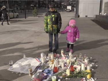 Youngsters look at a memorial outside the French consulate in Montreal Saturday, November 14 , 2015, in the morning prior to a large vigil for victims of the Paris terrorist attacks.