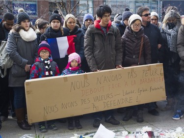 People stand outside the French consulate in Montreal on Sunday, Nov. 15, 2015 after a march in solidarity with Paris and the victims of the Paris terrorist attacks. The attacks Friday killed 127 people.