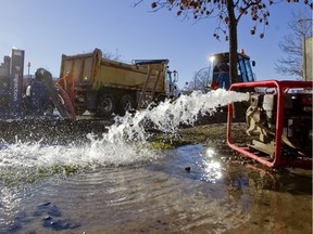 Workers pump water as they work to cap a water main break on Pierrefonds Blvd. at Paiement Street in Pierrefonds on November 16, 2015.  Several residents have ben without water since the leak erupted.  (Phil Carpenter / MONTREAL GAZETTE).