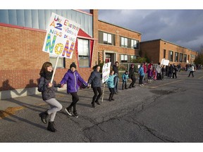 Students, parents, teachers, support staff and others, form a human chain in front of Ecole Saint-Michel in Vaudreuil-Dorion, west of Montreal, Monday November 2, 2015, to show their support for quality education at public schools in the face of proposed cuts by the provincial government.