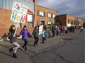 Students, parents, teachers, support staff and others, form a human chain in front of École Saint-Michel in Vaudreuil-Dorion, west of Montreal, Monday November 2, 2015, to show their support for quality education at public schools in the face of proposed cuts by the provincial government.  Several schools around the city held similar demonstrations.