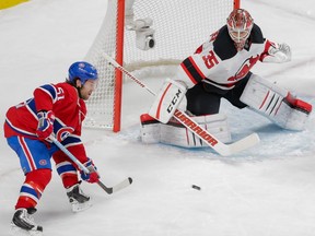 Montreal Canadiens centre David Desharnais, left, attempts to catch a pass as New Jersey Devils goalie Cory Schneider, right, looks on during their NHL hockey match at the Bell Centre in Montreal on Saturday, Nov. 28, 2015.