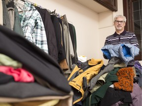 Paul Clarke, executive director of Action Refugies Montreal, sorts through a pile of donated winter coats in Montreal on Monday. The centre has been overwhelmed by the public donations in response to the Syrian refugee crisis.