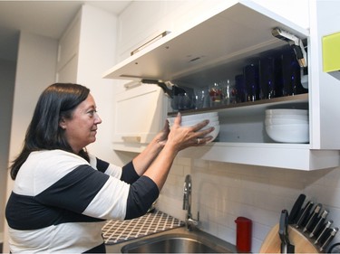 Terri Pulice puts bowls away in cupboards with horizontal opening doors in the condo she shares with her husband David Pecho in the Lachine borough of Montreal on Wednesday, October 7, 2015. (John Mahoney / MONTREAL GAZETTE)