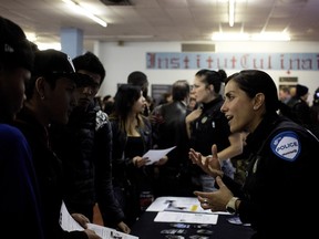 Montreal police officer Ingrid Cataldo speaks with participants at the St. Pius X Career Centre career fair in Montreal on Wednesday October 28, 2015.