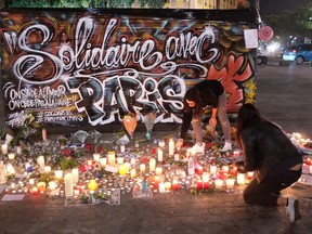 People place candles to pay tribute to the victims of the terror attacks in Paris by a poster which reads "Solidarity with Paris" in Nice, southeastern France, Monday, Nov. 16, 2015. France is urging its European partners to move swiftly to boost intelligence sharing, fight arms trafficking and terror financing, and strengthen border security in the wake of the Paris attacks.