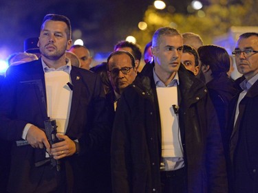 French President Francois Hollande (Rear C), protected by armed bodyguards, stands near the Bataclan concert hall in central Paris, early on November 14, 2015. At least 120 people were killed in a series of terror attacks in Paris on November 13 according to a provisional total, a source close to the investigation said.