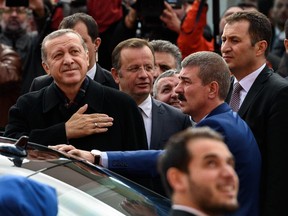 Turkish President Recep Tayyip Erdogan, left, gestures to supporters after casting his ballot for Turkey's legislative election at a polling station in Istanbul on November 1, 2015.