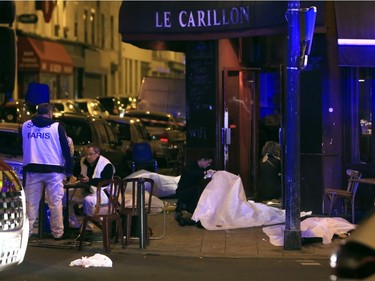 Victims lay on the pavement in a Paris restaurant, Friday, Nov. 13, 2015. Police officials in France on Friday reported a shootout in a Paris restaurant and an explosion in a bar near a Paris stadium.