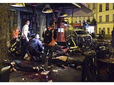 Victims of a shooting attack lay on the pavement outside La Belle Equipe restaurant in Paris Friday, Nov. 13, 2015.  Well over 100 people were killed in Paris on Friday night in a series of shooting, explosions.