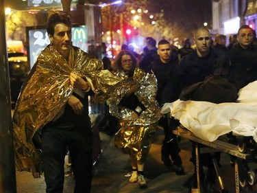 Victims walk away outside the Bataclan theater in Paris, Friday Nov. 13, 2015. Well over 100 people were killed  in a series of shooting and explosions explosions. French President Francois Hollande declared a state of emergency and announced that he was closing the country's borders.