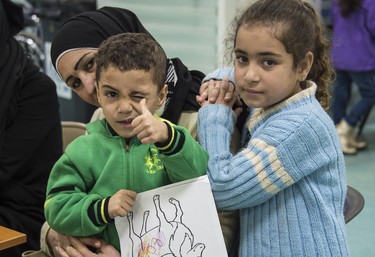 Two Syrian refugee children pose for the camera while their family under goes the medical screening portion of the Government of Canada's Operation Provision in Beirut, Lebanon Wednesday, Dec. 9, 2015. Crews from CFB Trenton's 427 Squadron are flying the first group of refugees to Toronto, landing there Friday, and the second group to Montreal Saturday.