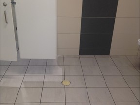 With his stomach heaving from the stench in the men's bathroom at the new Children's Hospital at the Glen site, Aaron Derfel used his iPhone to take a picture of the taped-over floor drain.