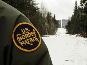 BEECHER FALLS, VT - MARCH 23:  A U.S. Border Patrol agent stands along the boundary marker cut into the forest marking the line between Canadian territory on the right and the United States March 23, 2006 near Beecher Falls, Vermont. As American politicians continue to debate immigration reform, Border Patrol agents work the northern border to prevent illegal entry.