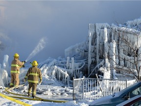Firefighters douse the burnt remains of a retirement home in L'Isle-Verte on January 23, 2014.