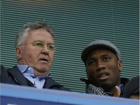 Chelsea's new manager Guus Hiddink, left, sits next to former Chelsea player Didier Drogba before the English Premier League soccer match between Chelsea and Sunderland at Stamford Bridge stadium in London, Saturday, Dec. 19, 2015. Guus Hiddink returned to Chelsea for a second spell as manager on Saturday, hired until the end of the season with the tough task of turning round the struggling Premier League champions following Jose Mourinho's firing.