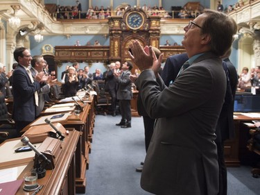 Opposition MNA Claude Cousineau, right, applauds with members of the legislature the presentation of people in the stands as the legislature resumes for its fall session, Tuesday, September 15, 2015 at the legislature in Quebec City. A motion to ban applause during question period is being studied by members of the legislature.