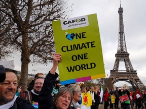 A demonstrator holds a banner reading "One climate one world" during a rally held by several Non Governmental Organisations (NGO)  to form a human chain on the Champs de Mars near the Eiffel Tower in Paris on December 12, 2015 on the sidelines of the COP21, the UN conference on global warming.