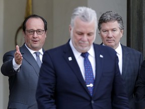 France's President Francois Hollande, left background, gestures toward Quebec Premier Philippe Couillard, after a meeting at the Elysee Palace, in Paris, Dec. 7, 2015.