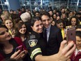 Canadian Prime Minister Justin Trudeau, right, poses for a selfies with workers before he greets refugees from Syria at Pearson International airport, in Toronto, on Thursday, Dec. 10, 2015.