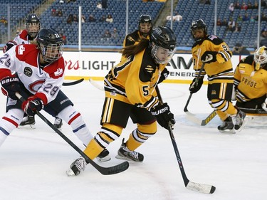Boston Prides' Kelly Cooke (5) handles the puck in front of Montreal Les Canadiennes' Marie-Philip Poulin during a women's outdoor hockey game at Gillette Stadium in Foxborough, Mass., Thursday, Dec. 31, 2015, where the Boston Bruins will play the Montreal Canadiens in the NHL Winter Classic on Friday.