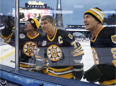Former Boston Bruins', from left, Ken Linseman, Ray Bourque and Steve Heinze search for people in the stands before an outdoor hockey game against fellow alumni from the Montreal Canadiens at Gillette Stadium in Foxborough, Mass., Thursday, Dec. 31, 2015, where the Bruins will play the Canadiens in the NHL Winter Classic on Friday.