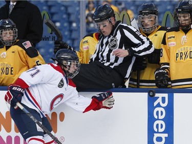 Les Canadiennes' Leslie Oles (71) reaches for the puck in front of the Boston Pride's bench during an outdoor women's hockey game at Gillette Stadium in Foxborough, Mass., Thursday, Dec. 31, 2015, where the Boston Bruins will play the Montreal Canadiens in the NHL Winter Classic on Friday.