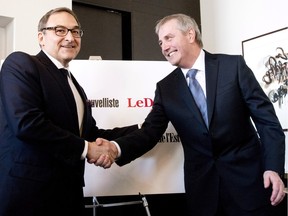 Martin Cauchon, owner of Groupe Capitales Médias, which includes Le Soleil, and Claude Gagnon, president and director general, shake hands after they announced the purchase of six newspapers that were owned by Gesca, Wednesday, March 18, 2015 in Quebec City.