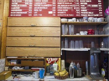 The wall behind the counter, below the menu his closed shelves where cigarettes are hidden at Moe's-Casse-Croute-du-Coin Friday, December 4, 2015.