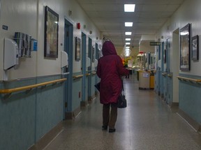 A woman carries flowers as she walks down the corridor toward a room in the palliative care centre of a Montreal hospital, Tuesday Dec. 1, 2015.
