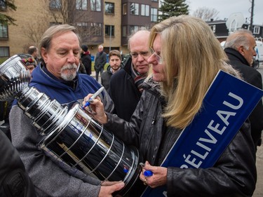 Helene Beliveau, daughter of hockey great Jean Beliveau, writes the date on the imitation Stanley Cup belonging to Beliveau admirer Gerry Bibeault, left, during a ceremony to announce the renaming of Victoria street to Jean-Beliveau street in Longueuil on Tuesday, December 1, 2015. Bibeault said he met Jean Beliveau many times at the Montreal General Hospital when he was assigned to take blood samples from the hockey Hall of Fame player. The renaming coincides with the one-year anniversary of the death of hockey great Jean Beliveau on December 2, 2014.