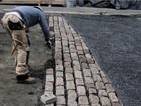 Workers lay stones to build a cobblestone road surface on St-Gabriel St. in Old Montreal.