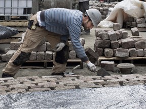 Workers lay stones to build a cobblestone road surface on Saint-Gabriel in Old Montreal Dec. 11, 2015.