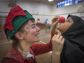 Camille Cormier Trudel, left, outfits 3-year-old Taneen Ibrahim with a clown nose at a Christmas party in Verdun on Saturday for refugees who have arrived in Canada this year.