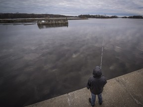 A fisherman takes advantage of the warmer weather to do some angling in Lac des Deux Montagnes off the shore of Ste-Anne-de- Bellevue Sunday, Dec. 13, 2015.