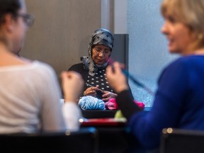 Montrealer Aicha Saik, centre, knits a toque at the McCord Museum in December to donate to a Syrian refugee coming to Canada. The museum was a dropoff point for the project.