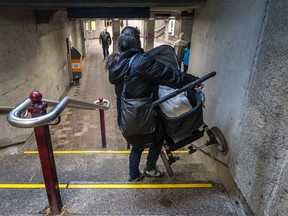 A mother awkwardly carries her baby down the stairs at the Vendome métro station Dec. 16, 2015 to the underground tunnel that connects to the MUHC Glen site.