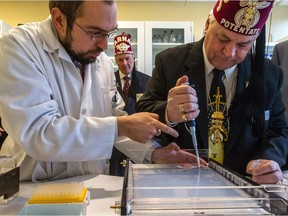 Martin Pellicelli gives a how-to lesson in DNA extraction to Brian Terin of the Winnipeg Shriners at  the new research centre opened by the Shriners Hospital in Montreal.