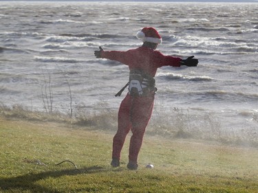 William Pollock, dressed in a Santa Claus suit, stands against the wind as he is sprayed by water from Lac St. Louis, while he waits for wind to die down in Dorval, Montreal, Wednesday December 24, 2015.  He was hoping to kiteboard but the winds were too strong.  Gusts of up tp 90 km/hr knocked out power in some places.  Record warm temperatures of around 16 degrees Celcius in the Montreal area had many people windsurfing, among other outdoor activities typiclly associated with warm weather.
