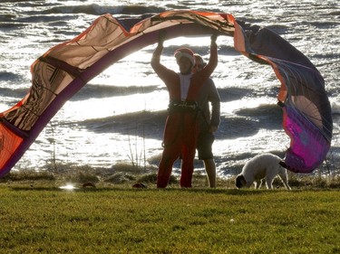 William Pollock, dressed in a Santa Claus suit, prepares his kite for kiteboarding, as Jeremey Goldenberg watches, while Pollock waits for strong winds to die down on Lac st Louis in Dorval, Montreal, Wednesday December 24, 2015.  He wasn't able to kiteboard in the end because the winds were too strong, and gusts of up to 90 km/hr knocked out power in some places in the province.  Record warm temperatures of around 16 degrees Celcius in the Montreal area had many people windsurfing, among other outdoor activities typiclly associated with warm weather.
