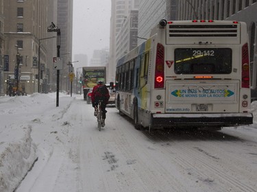 A bicycle messenger is forced on to de Maisonneuve Boulevard in Montreal on Tuesday December 29, 2015. Bike paths were not cleared as Montreal received its first major snow fall after a very warm start to the winter.