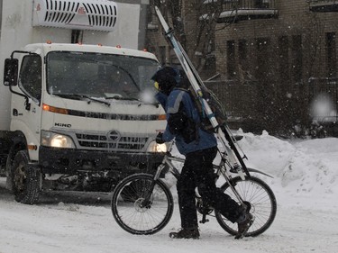 A cyclist pushes his bike along Atwater Avenue while carrying skis in Montreal on Tuesday December 29, 2015.